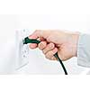 Hand inserting green electrical plug into outlet