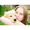 Portrait of smiling teenage girl holding golden retriever puppy