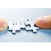 Fingers pushing two matching puzzle pieces together