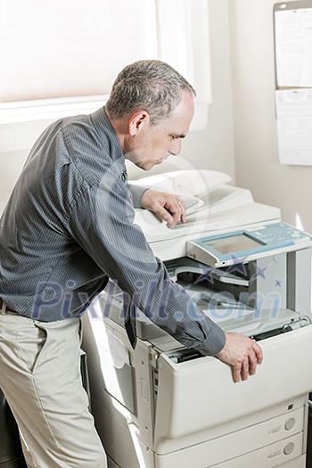 Business man opening photocopy machine in office Business man opening photocopy machine in office