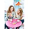 Two smiling women meeting for coffee in cafe and laughing