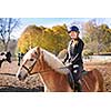Portrait of teenage girl riding horse outdoors on sunny autumn day
