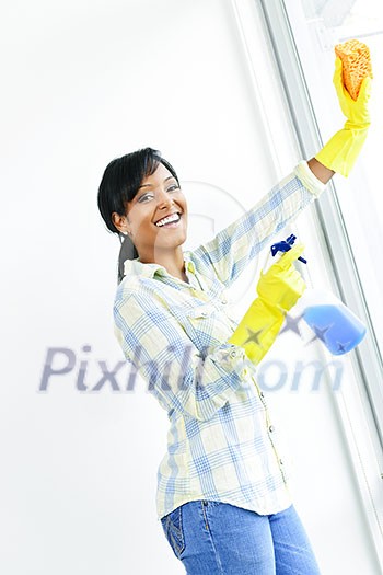 Smiling black woman cleaning windows with glass cleaner Smiling black woman cleaning windows with glass cleaner