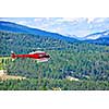 Red rescue helicopter flying emergency mission in mountains, Alberta Canada
