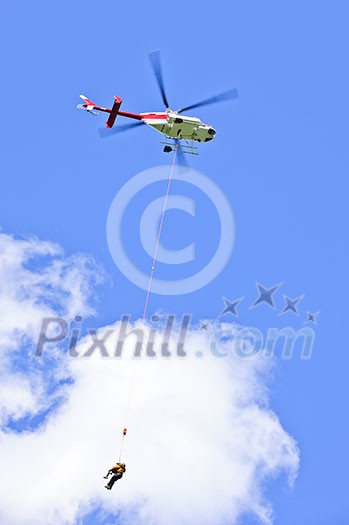 Rescue helicopter rescuing person by airlifting dangling on rope Rescue helicopter rescuing person by airlifting dangling on rope