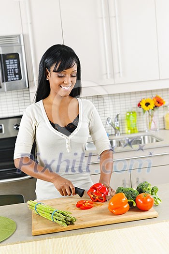 Smiling black woman cutting vegetables in modern kitchen interior Smiling black woman cutting vegetables in modern kitchen interior
