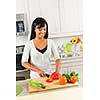 Smiling black woman cutting vegetables in modern kitchen interior