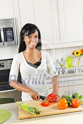 Smiling black woman cutting vegetables in modern kitchen interior Smiling black woman cutting vegetables in modern kitchen interior