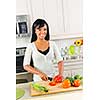 Smiling black woman cutting vegetables in modern kitchen interior