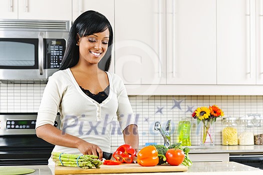 Smiling black woman cutting vegetables in modern kitchen interior Smiling black woman cutting vegetables in modern kitchen interior