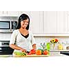 Smiling black woman cutting vegetables in modern kitchen interior