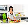 Smiling black woman cutting vegetables in modern kitchen interior