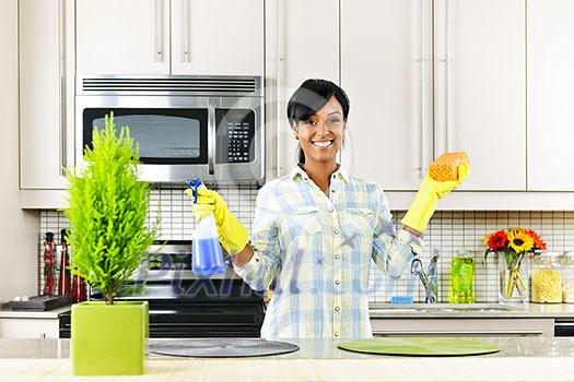 Smiling young black woman with sponge and rubber gloves cleaning kitchen Smiling young black woman with sponge and rubber gloves cleaning kitchen