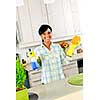 Smiling young black woman with sponge and rubber gloves cleaning kitchen