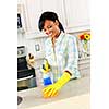 Smiling young black woman with sponge and rubber gloves cleaning kitchen
