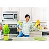 Smiling young black woman dancing and enjoying cleaning kitchen