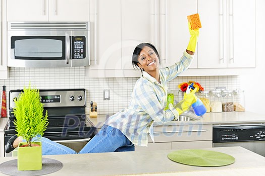 Smiling young black woman dancing and enjoying cleaning kitchen Smiling young black woman dancing and enjoying cleaning kitchen