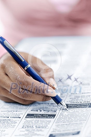 Black female hand circling ad in newspaper classified section looking for job Black female hand circling ad in newspaper classified section looking for job
