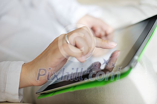 Young woman at home relaxing in her lliving room reading a digital tablet PC surf internet and work