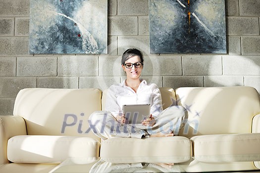 Young woman at home relaxing in her lliving room reading a digital tablet PC surf internet and work