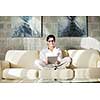 Young woman at home relaxing in her lliving room reading a digital tablet PC surf internet and work