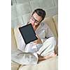 Young woman at home relaxing in her lliving room reading a digital tablet PC surf internet and work