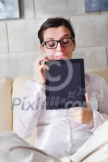 Young woman at home relaxing in her lliving room reading a digital tablet PC surf internet and work Young woman at home relaxing in her lliving room reading a digital tablet PC surf internet and work