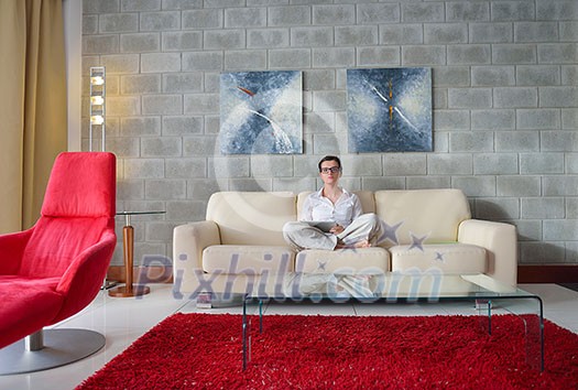 Young woman at home relaxing in her lliving room reading a digital tablet PC surf internet and work Young woman at home relaxing in her lliving room reading a digital tablet PC surf internet and work