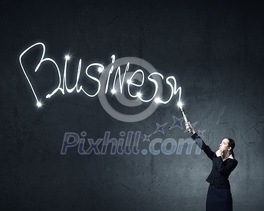 Businesswoman in darkness drawing business word with flashlight Businesswoman in darkness drawing business word with flashlight