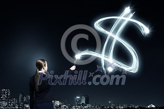 Businesswoman in darkness drawing dollar sign with flashlight