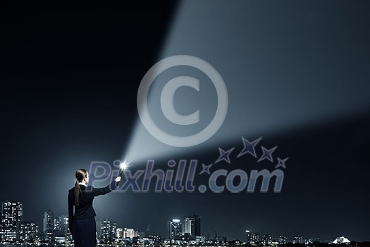 Businesswoman in darkness with flashlight in hand Businesswoman in darkness with flashlight in hand