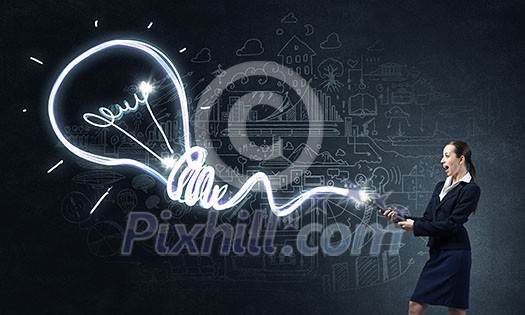 Businesswoman in darkness drawing light bulb with flashlight Businesswoman in darkness drawing light bulb with flashlight