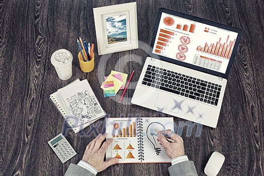 Top view of business workplace and businessman hands writing in notepad Top view of business workplace and businessman hands writing in notepad