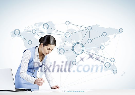 Beautiful young lady at desk working on laptop with social network concept Beautiful young lady at desk working on laptop with social network concept