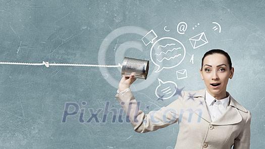 Young pretty businesswoman attaching tin phone to ear Young pretty businesswoman attaching tin phone to ear
