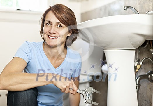 Confident woman repairing sink in bathroom at home Confident woman repairing sink in bathroom at home