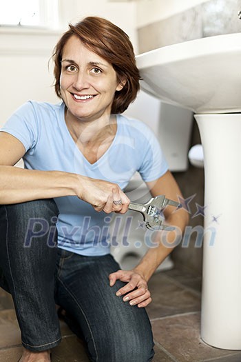 Confident woman repairing sink in bathroom at home Confident woman repairing sink in bathroom at home