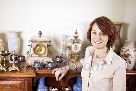 Happy proud woman standing next to her collection of antiques Happy proud woman standing next to her collection of antiques