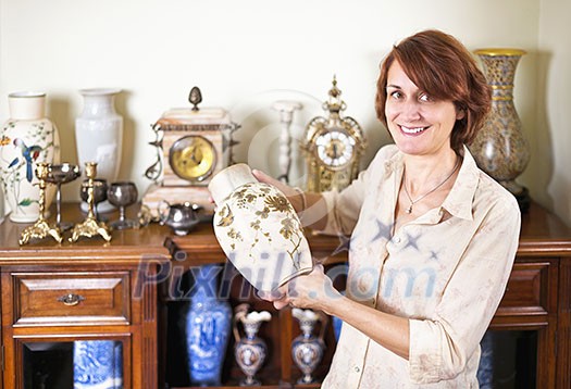 Proud woman holding vase from her collection of antiques Proud woman holding vase from her collection of antiques
