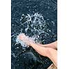 Girl sitting on dock splashing bare legs in lake