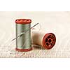 Two spools of thread with needle for sewing