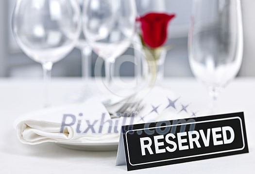 Reserved romantic restaurant table setting with roses plates and cutlery Reserved romantic restaurant table setting with roses plates and cutlery
