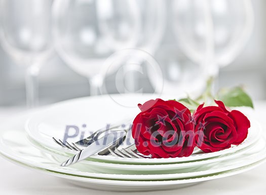 Romantic restaurant table setting for two with roses plates and cutlery Romantic restaurant table setting for two with roses plates and cutlery