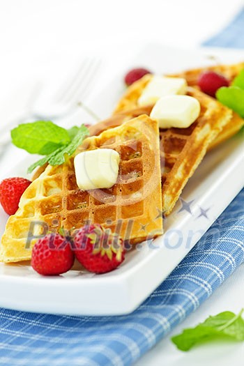 Plate of belgian waffles with fresh strawberries and pats of butter Plate of belgian waffles with fresh strawberries and pats of butter