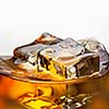 Splash of whiskey with ice in glass isolated on white background