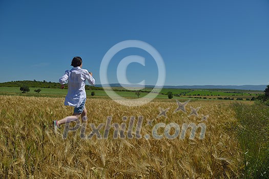 Young woman standing jumping and running on a wheat field with blue sky in background at summer day representing healthy life and agriculture concept Young woman standing jumping and running on a wheat field with blue sky in background at summer day representing healthy life and agriculture concept