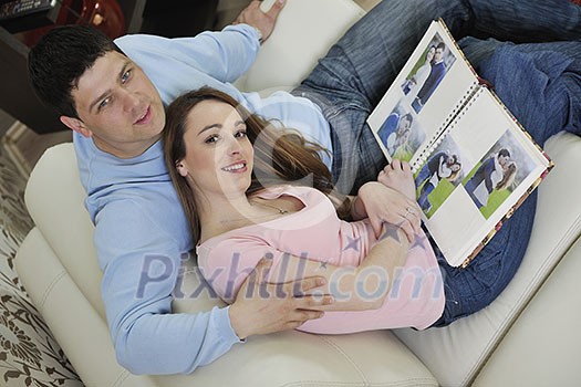 happy young couple looking old pictures in photo album at home happy young couple looking old pictures in photo album at home