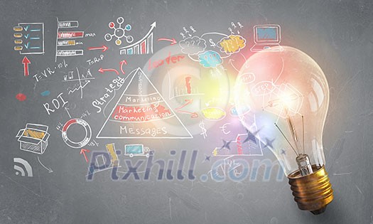 Glass glowing light bulb and business sketched ideas Glass glowing light bulb and business sketched ideas