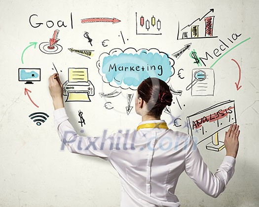 Businesswoman standing with back drawing business ideas on wall Businesswoman standing with back drawing business ideas on wall