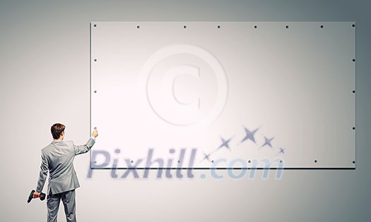 Rear view of businessman fixing white blank banner with drill Rear view of businessman fixing white blank banner with drill